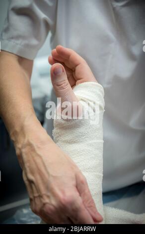 Krankenschwester, die den Arm eines Patienten in einem Krankenhaus in einer Unfall- und Notaufnahme in England plaziert. Stockfoto