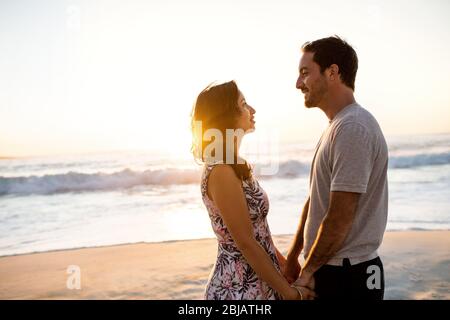 Liebende Paare, die sich gegenseitig in die Augen schauen, an einem Strand Stockfoto