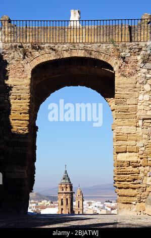 Blick durch den Giants Bogen (Arco de los Gigantes) in Richtung Kirchtürme und Stadthäuser, Antequera, Provinz Málaga, Andalusien, Spanien. Stockfoto