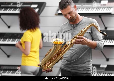 Schöner Mann, der Saxophon im Musikgeschäft spielt Stockfoto