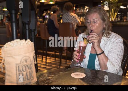 dh Long Barbeutel mit Erdnüssen RAFFLES HOTEL SINGAPUR-Touristen, die eine Singapur-Schlinge trinken Stockfoto