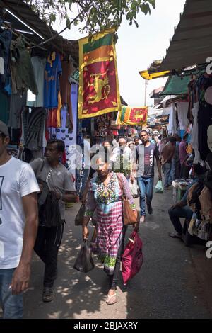 dh Sri lanka Flagge COLOMBO MARKT SRI LANKA ASIEN Lokal asiatische Straße Menschen Fahnen angezeigt Frau tragen von Einkaufen Stockfoto