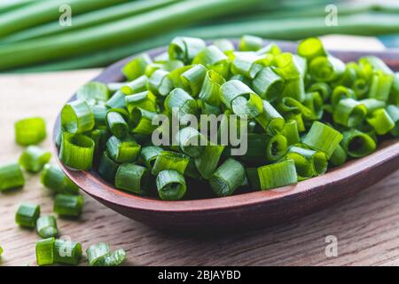 Frische grüne Zwiebel gehackt und liegt auf einer Schüssel auf einem Schneidebrett auf einem Hintergrund von blauen Brettern. Zwiebeln sind reich an Vitaminen und Mineralstoffen. Stockfoto