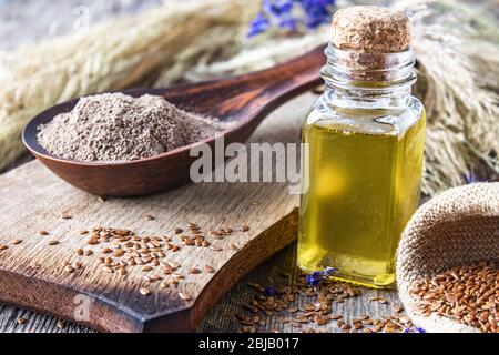 Leinsamenöl in einer Flasche in der Nähe der gehackten Leinsamen in einem Löffel. Leinsamenöl wird in der Küche, Medizin, Kosmetik verwendet. Stockfoto