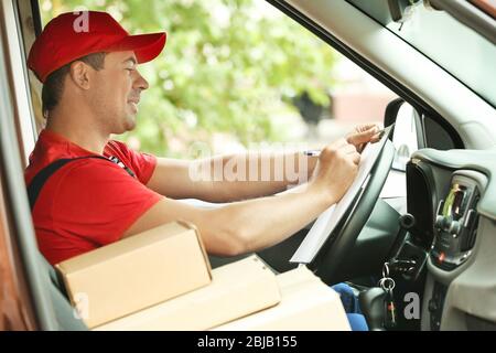 Bereitstellungskonzept. Postbote prüft Bestellungen in einem Auto Stockfoto