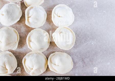 Rohe Knödel mit Hackfleisch auf dem Tisch. Der Prozess der Herstellung von hausgemachten Knödeln. Russische nationale Küche. Stockfoto