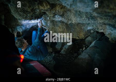 Der Mensch macht einen Felsbrocken in der Twardowski Höhle. Bouldern im Fels. Twardowski Höhle Stockfoto