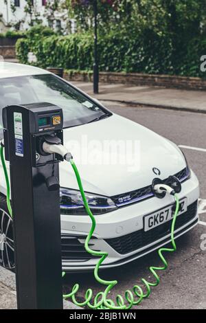 London/UK-30/07/18: Weiße Volkswagen Golf GTE-Autos laden an einer Ladestation auf einer Straße in London. Der Golf GTE ist eine Plug-in-Hybrid-Version des Stockfoto