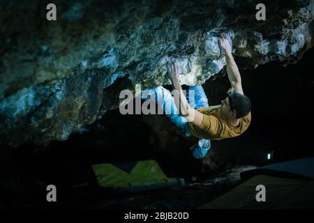Der Mensch macht einen Felsbrocken in der Twardowski Höhle. Bouldern im Fels. Twardowski Höhle Stockfoto