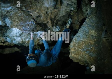 Der Mensch macht einen Felsbrocken in der Twardowski Höhle. Bouldern im Fels. Twardowski Höhle Stockfoto