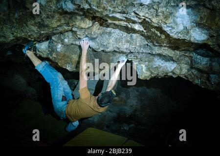 Der Mensch macht einen Felsbrocken in der Twardowski Höhle. Bouldern im Fels. Twardowski Höhle Stockfoto