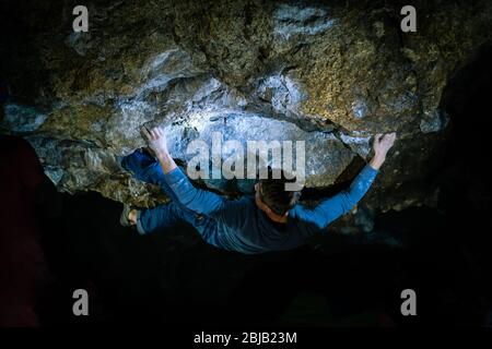 Der Mensch macht einen Felsbrocken in der Twardowski Höhle. Bouldern im Fels. Twardowski Höhle Stockfoto
