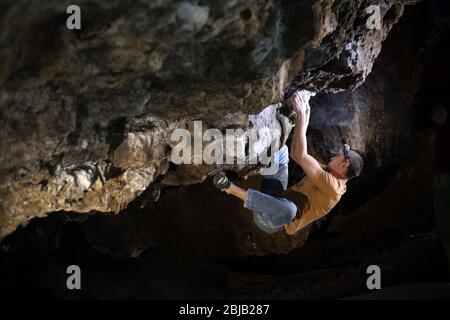 Der Mensch macht einen Felsbrocken in der Twardowski Höhle. Bouldern im Fels. Twardowski Höhle Stockfoto