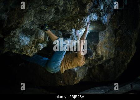 Der Mensch macht einen Felsbrocken in der Twardowski Höhle. Bouldern im Fels. Twardowski Höhle Stockfoto