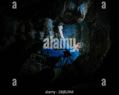 Der Mensch macht einen Felsbrocken in der Twardowski Höhle. Bouldern im Fels. Twardowski Höhle Stockfoto