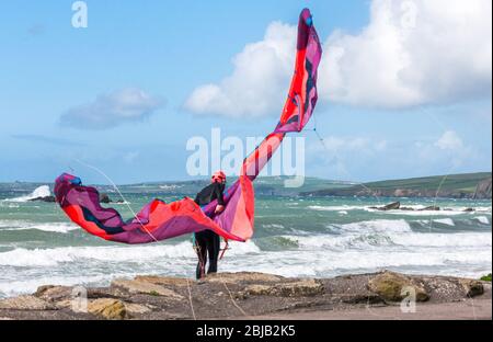 Garrettstown, Cork, Irland. April 2020. Ein Einheimischer kämpft, um seinen Drachen bei hohem Wind zu kontrollieren, während er sich auf einen Morgen des Surfens am Garrettstown Beach in Co. Cork, Irland, vorbereitet. - Credit; David Creedon / Alamy Live News Stockfoto