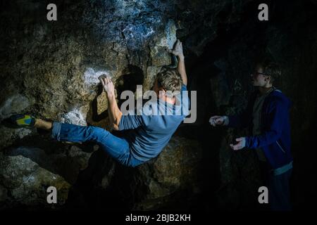 Der Mensch macht einen Felsbrocken in der Twardowski Höhle. Bouldern im Fels. Twardowski Höhle Stockfoto