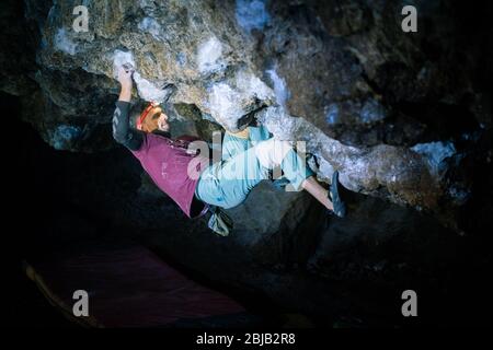 Der Mensch macht einen Felsbrocken in der Twardowski Höhle. Bouldern im Fels. Twardowski Höhle Stockfoto