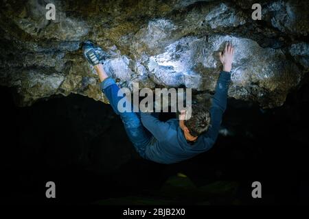 Der Mensch macht einen Felsbrocken in der Twardowski Höhle. Bouldern im Fels. Twardowski Höhle Stockfoto