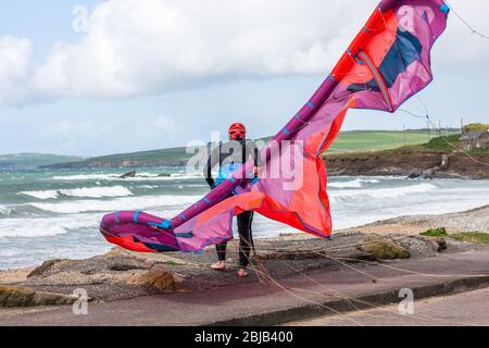 Garrettstown, Cork, Irland. April 2020. Ein Einheimischer kämpft, um seinen Drachen bei hohem Wind zu kontrollieren, während er sich auf einen Morgen des Surfens am Garrettstown Beach in Co. Cork, Irland, vorbereitet. - Credit; David Creedon / Alamy Live News Stockfoto