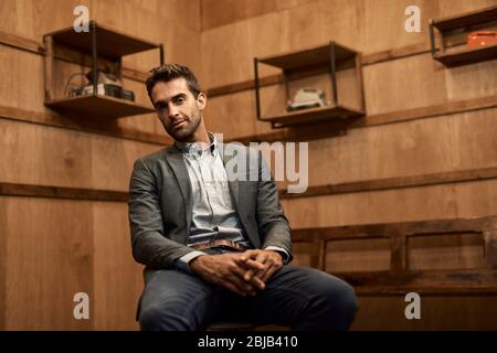Ein stilvoller Mann sitzt auf einem Stuhl in einer trendigen Lounge Stockfoto