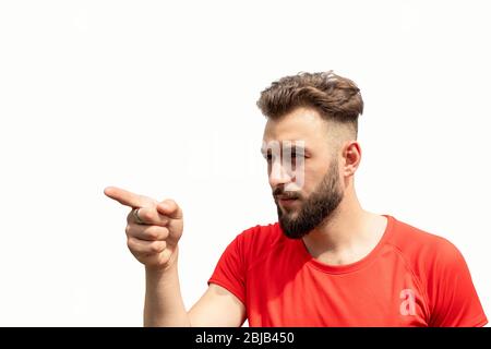 Taille oben des jungen bärtigen Mannes in rot mit verächtlichen, anklagerenden Ausdruck, zeigt Finger auf links auf jemand isoliert auf weiß Stockfoto