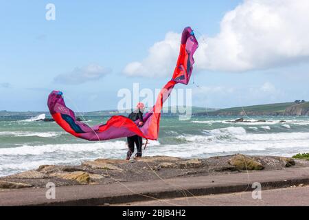 Garrettstown, Cork, Irland. April 2020. Ein Einheimischer kämpft, um seinen Drachen bei hohem Wind zu kontrollieren, während er sich auf einen Morgen des Surfens am Garrettstown Beach in Co. Cork, Irland, vorbereitet. - Credit; David Creedon / Alamy Live News Stockfoto