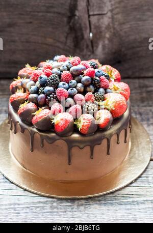 Schokoladenkuchen mit frischen Sommerbeeren. Dekoriert mit Erdbeeren, die in geschmolzene Schokolade getaucht sind. Stockfoto