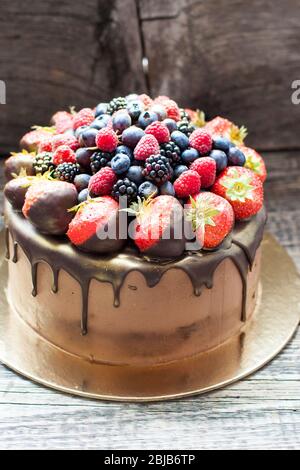 Schokoladenkuchen mit frischen Sommerbeeren. Dekoriert mit Erdbeeren, die in geschmolzene Schokolade getaucht sind. Stockfoto