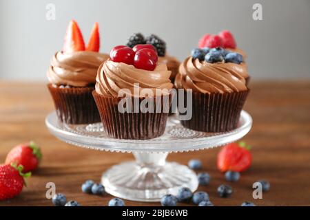 Leckere Schokoladen-Cupcakes mit frischen Beeren auf dem Stand Stockfoto