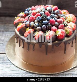 Schokoladenkuchen mit frischen Sommerbeeren. Dekoriert mit Erdbeeren, die in geschmolzene Schokolade getaucht sind. Stockfoto