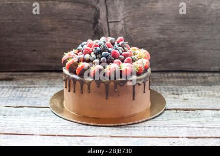 Schokoladenkuchen mit frischen Sommerbeeren. Dekoriert mit Erdbeeren, die in geschmolzene Schokolade getaucht sind. Stockfoto