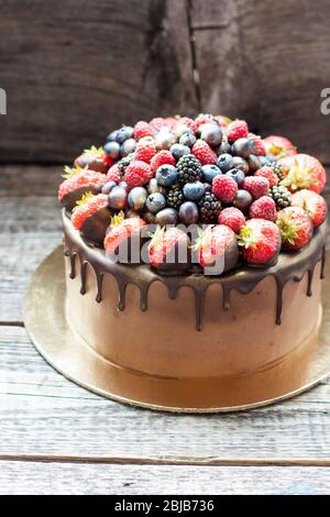Schokoladenkuchen mit frischen Sommerbeeren. Dekoriert mit Erdbeeren, die in geschmolzene Schokolade getaucht sind. Stockfoto