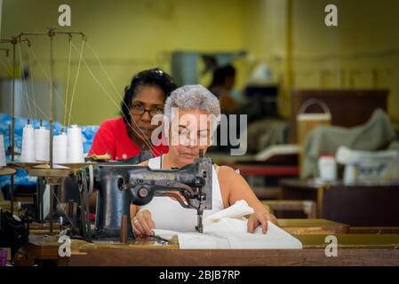 Havanna, Kuba. Frauen in einer Bekleidungsfabrik, Nähfirma. Die Kleiderfabriken sind schlecht ausgestattet, die Arbeiter müssen alte Nähmaschinen benutzen. Stockfoto