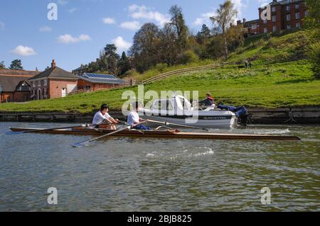 Zwei Männer in einer Rudern Scull Blick auf ein motorbetriebenes Boot sie auf dem Fluss Severn in Shrewsbury UK passieren Stockfoto