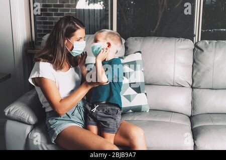 Mutter und Kind tragen Facemask während des Coronavirus- und Grippeausbruchs zu Hause. Virenschutz. Mutter und Sohn versuchen, die Ausbreitung der Krankheit zu stoppen. Stockfoto