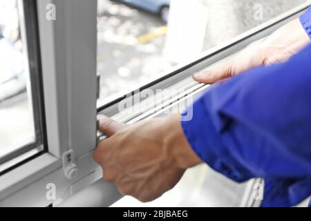 Bauarbeiter, der Schaumstoffklebeband an Fenster im Haus klebt Stockfoto