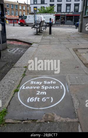 Lockdown London, 29. April 2020: Sprühbemaltes Graffiti auf dem Bürgersteig, das die Menschen an die 2 Meter soziale Distanz erinnert, die während der Lockdown in London erforderlich ist Stockfoto