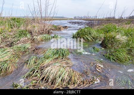 Bewegungsunschärfe des Wassers, das in der Farm Field Waterway in Graben fließt, nachdem heftiger Regen und Stürme Überschwemmungen verursacht haben. Konzept der Bodenerosionskontrolle Stockfoto