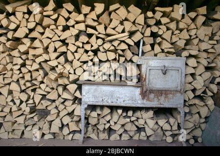 Alter Herd/Herd mit gestapeltem Holz im Rücken Stockfoto