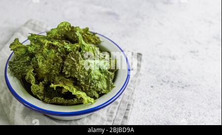 Grünkohl Chips mit Salz auf Teller. Hausgemachten gesunden Snack für low carb, Keto, kalorienarme Ernährung. Grauzement Hintergrund. Ready-to-kale Chips essen, kopieren Platz für Text. Banner Stockfoto