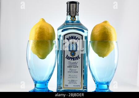 Flasche Bombay Sapphire Gin mit zwei Kelchen und Zitronen weißen Hintergrund Stockfoto