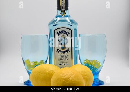 Flasche Bombay Sapphire Gin mit zwei Kelchen und Zitronen weißen Hintergrund Stockfoto