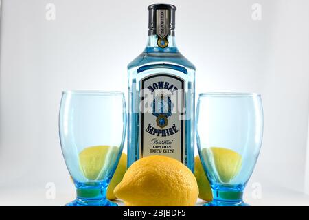 Flasche Bombay Sapphire Gin mit zwei Kelchen und Zitronen weißen Hintergrund Stockfoto