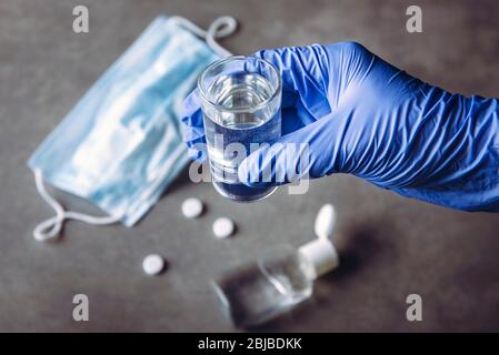 Alkoholproblem Alkoholismus während der Coronavirus Isolation Quarantäne Zeitkonzept. Hand mit medizinischen Handschuh hält Schuss mit Alkohol trinken. Pillen, Hand Stockfoto