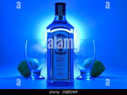 Flasche Bombay Sapphire Gin mit Kelchen und Zitronen blauen Hintergrund Stockfoto