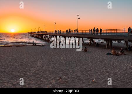 Adelaide, South Australia - 9. März 2018: Glenelg Beach mit Steg voller Menschen, die sich an einem heißen Sommerabend entspannen Stockfoto