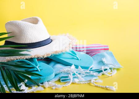 Strandstroh Sonnenhut, Handtuch, Accessoires auf gelb. Sommer Urlaub Hintergrund. Platz für Text. Stockfoto