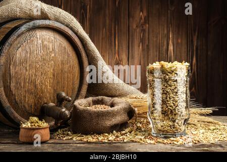 Bierfass mit Hopfen und Gerste auf Holzhintergrund Stockfoto