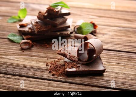 Dunkle Schokoladenstücke mit Minzblättern auf Holztisch Stockfoto